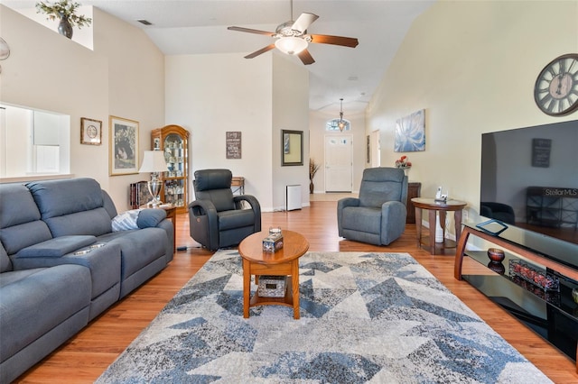 living room with hardwood / wood-style flooring, ceiling fan, and high vaulted ceiling