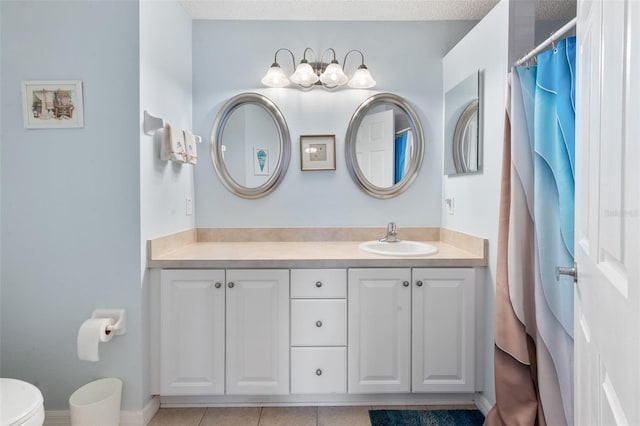 bathroom with vanity, toilet, tile patterned flooring, and a textured ceiling