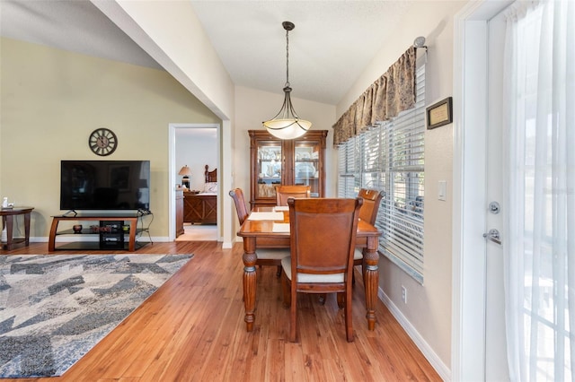 dining room featuring lofted ceiling and light hardwood / wood-style flooring