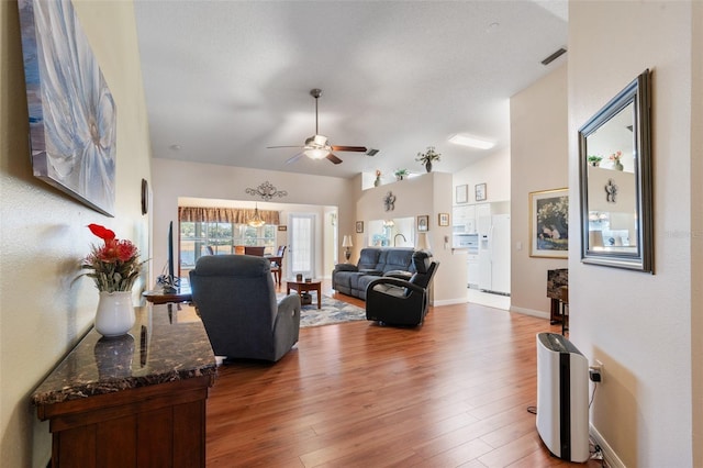 living room with wood-type flooring, ceiling fan, and vaulted ceiling