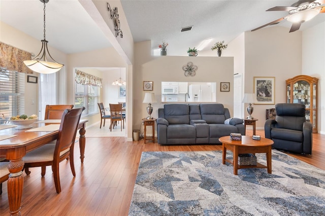 living room featuring hardwood / wood-style flooring, vaulted ceiling, ceiling fan, and a textured ceiling