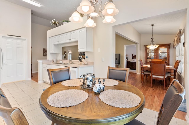 tiled dining area with lofted ceiling, sink, and a notable chandelier