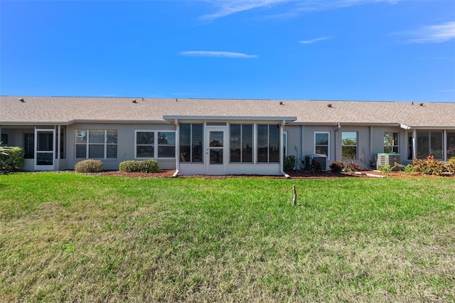 rear view of house with central AC, a lawn, and a sunroom