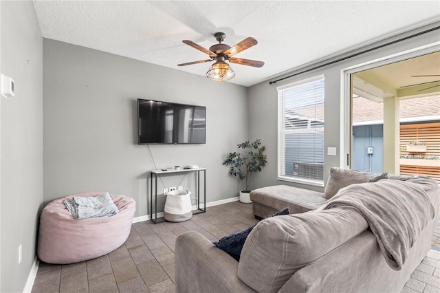 living room featuring ceiling fan and a textured ceiling