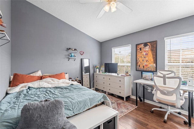 bedroom with a textured ceiling, ceiling fan, dark wood-type flooring, and vaulted ceiling