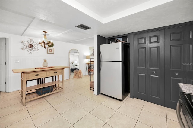 kitchen with range with electric stovetop, light tile patterned floors, a notable chandelier, and white refrigerator