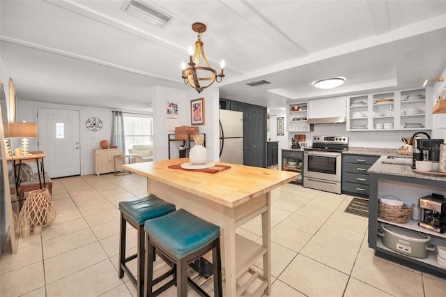 kitchen featuring white cabinets, sink, appliances with stainless steel finishes, light tile patterned flooring, and a chandelier