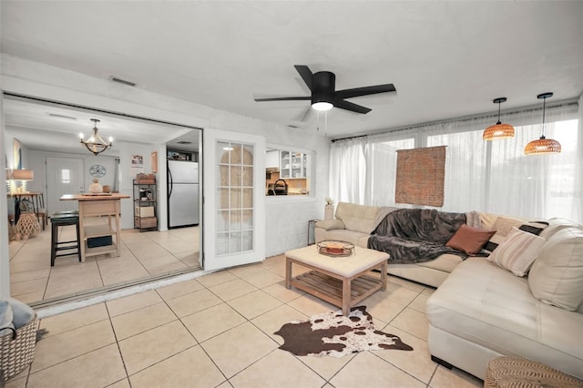 tiled living room with ceiling fan with notable chandelier