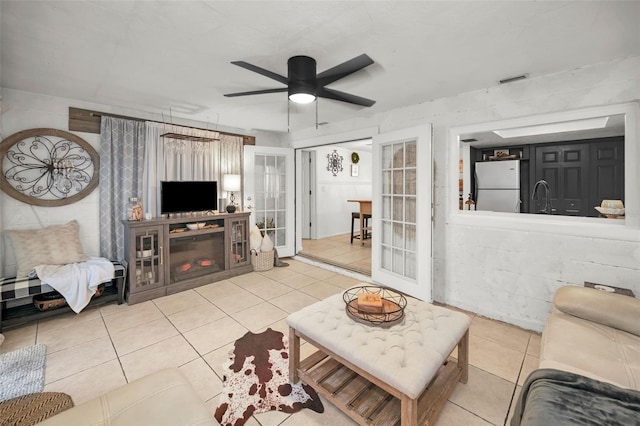 living room featuring french doors, light tile patterned floors, ceiling fan, and sink