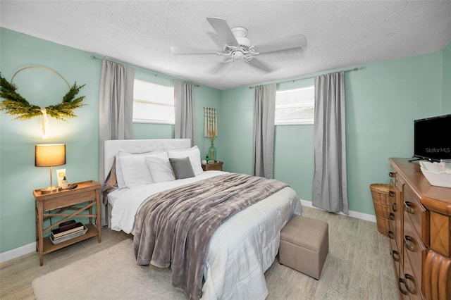 bedroom featuring ceiling fan, light hardwood / wood-style flooring, and a textured ceiling