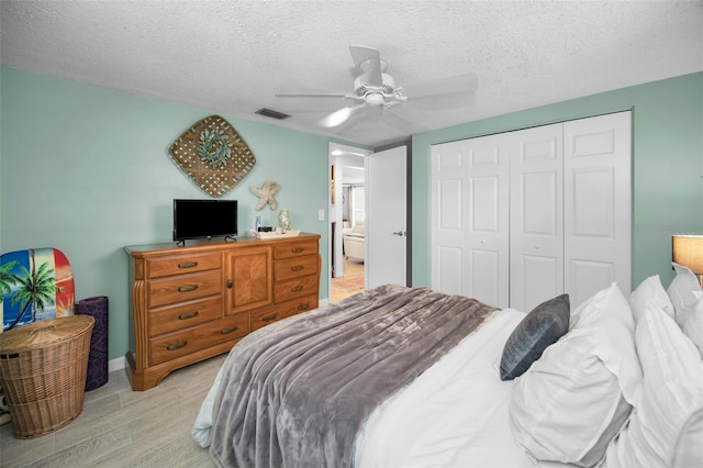 bedroom featuring ceiling fan, light hardwood / wood-style floors, a textured ceiling, and a closet