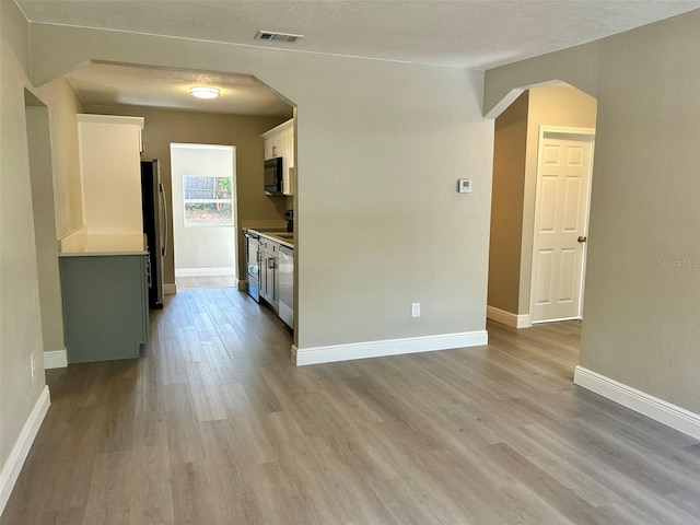 kitchen featuring stainless steel fridge, light wood-type flooring, white cabinetry, and range with electric cooktop