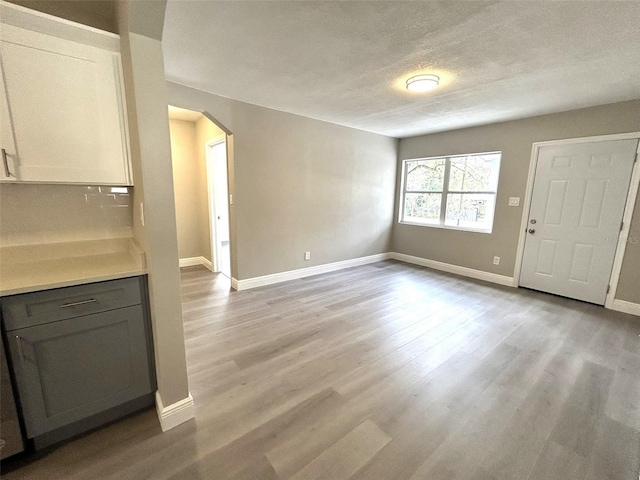 unfurnished living room featuring a textured ceiling and light hardwood / wood-style flooring