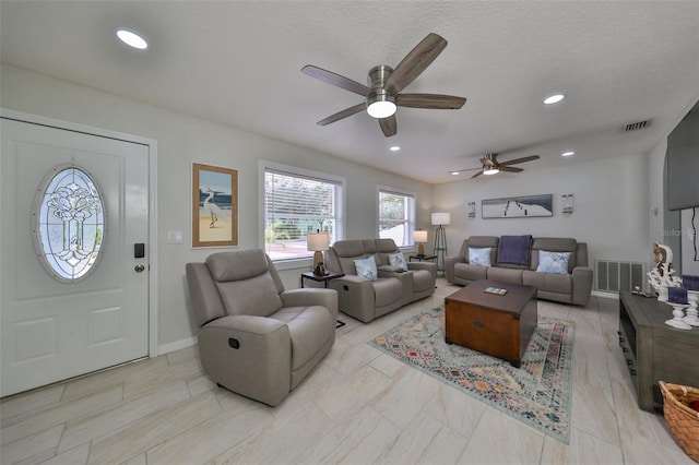 living room featuring ceiling fan and a textured ceiling