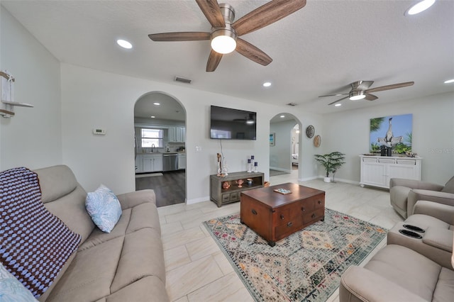 living room featuring a textured ceiling, ceiling fan, and sink