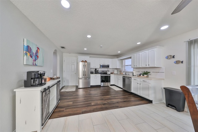 kitchen featuring a textured ceiling, stainless steel appliances, ceiling fan, sink, and white cabinets