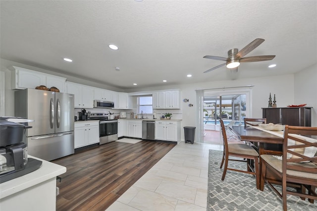 kitchen with white cabinets, sink, ceiling fan, a textured ceiling, and appliances with stainless steel finishes