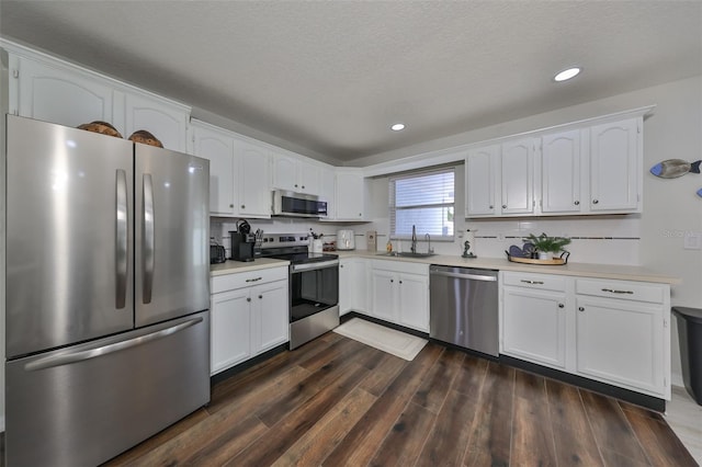 kitchen with white cabinets, sink, appliances with stainless steel finishes, and dark wood-type flooring