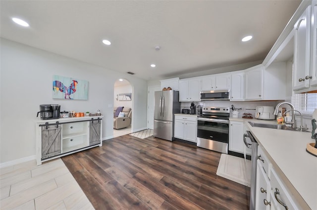 kitchen featuring white cabinetry, sink, stainless steel appliances, tasteful backsplash, and hardwood / wood-style flooring