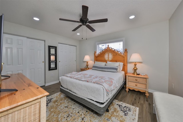 bedroom featuring two closets, a textured ceiling, dark hardwood / wood-style floors, and ceiling fan