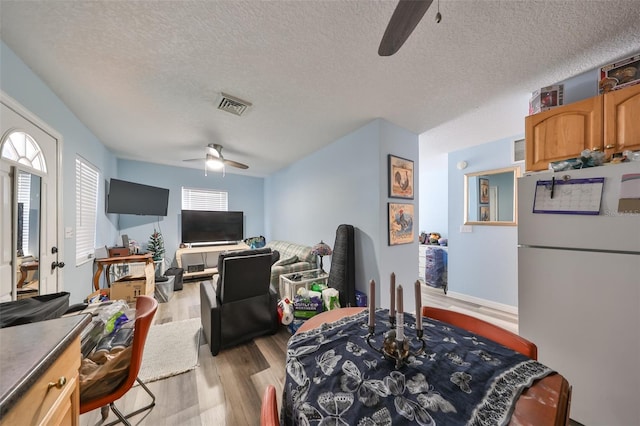 dining room featuring ceiling fan, light hardwood / wood-style floors, and a textured ceiling