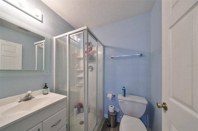 bathroom featuring vanity, a shower with shower door, a textured ceiling, and toilet