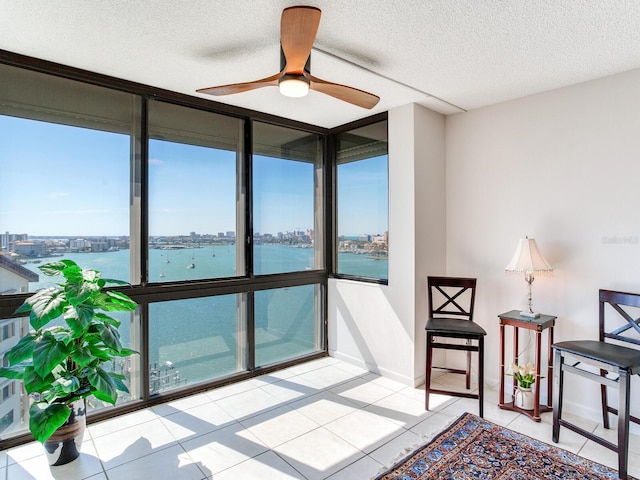 sunroom featuring a water view, ceiling fan, and a healthy amount of sunlight