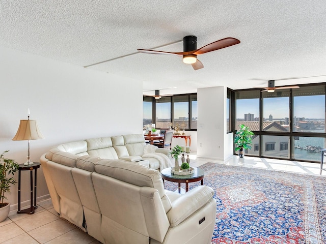 living room with a textured ceiling, ceiling fan, and light tile patterned flooring