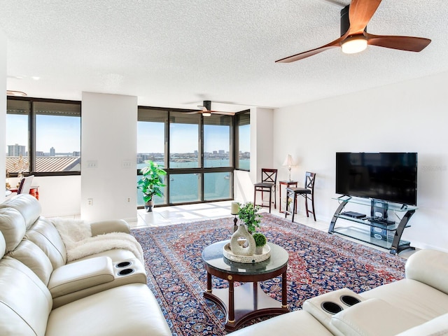 living room featuring ceiling fan, a wall of windows, and a textured ceiling