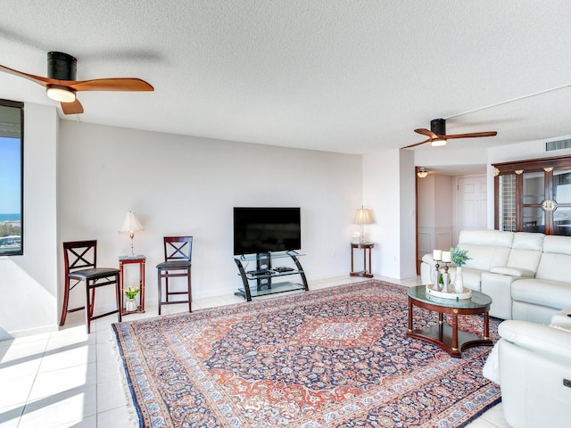 living room featuring ceiling fan, light tile patterned floors, and a textured ceiling