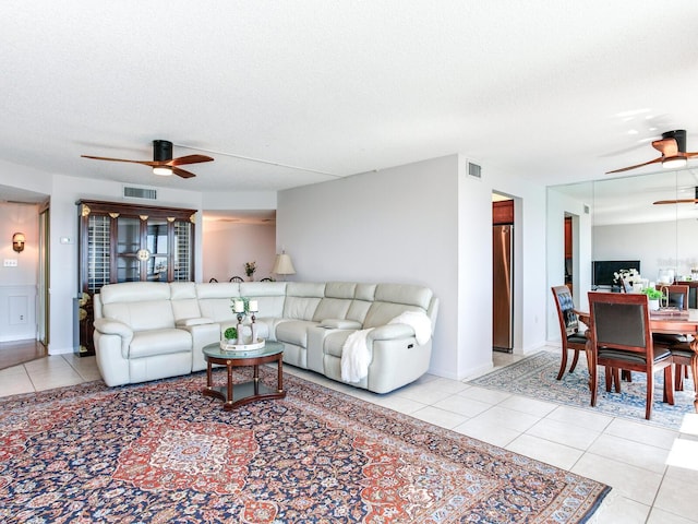 living room featuring ceiling fan, light tile patterned flooring, and a textured ceiling