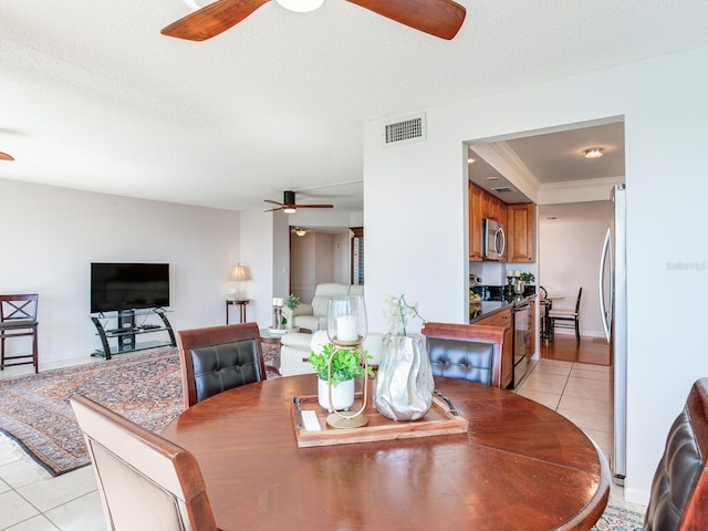 dining room with a textured ceiling, ornamental molding, and light tile patterned flooring