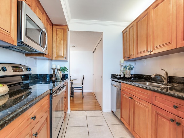 kitchen featuring dark stone countertops, crown molding, light tile patterned flooring, and appliances with stainless steel finishes