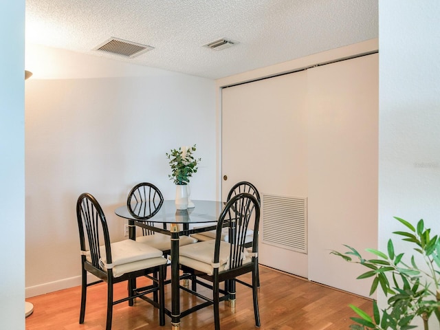 dining room with hardwood / wood-style flooring and a textured ceiling