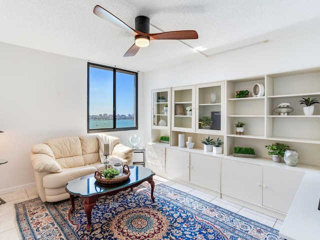 living room featuring ceiling fan, light tile patterned floors, and a textured ceiling