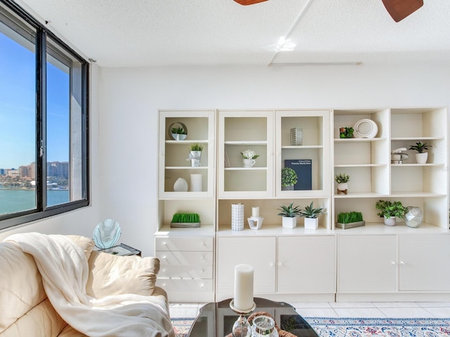 living area with light tile patterned floors, a textured ceiling, and ceiling fan