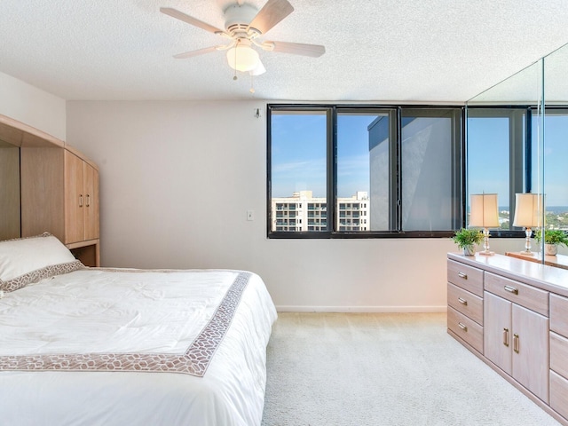 carpeted bedroom featuring ceiling fan and a textured ceiling