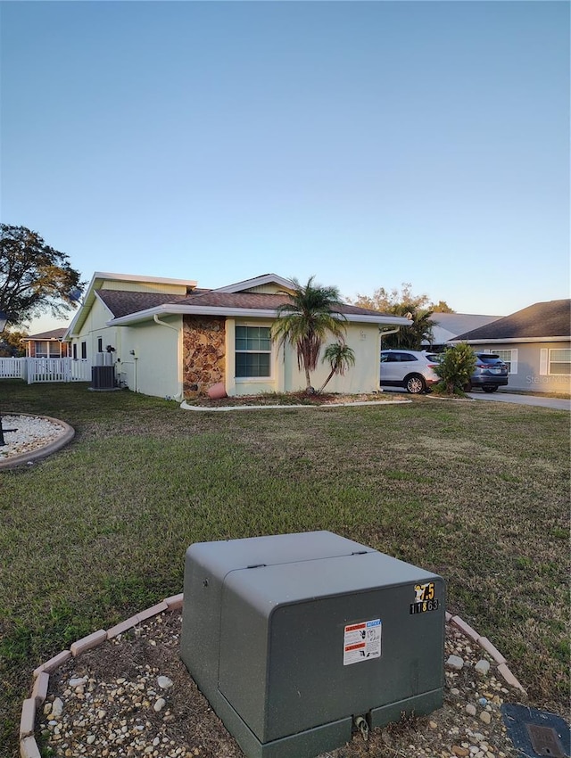 ranch-style home featuring cooling unit and a front lawn