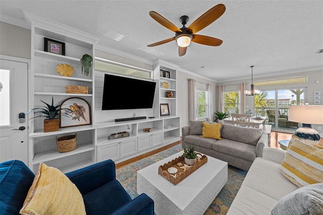 living room with ceiling fan with notable chandelier, a textured ceiling, dark wood-type flooring, and ornamental molding