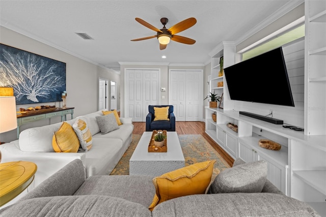 living room with a textured ceiling, hardwood / wood-style flooring, ceiling fan, and ornamental molding