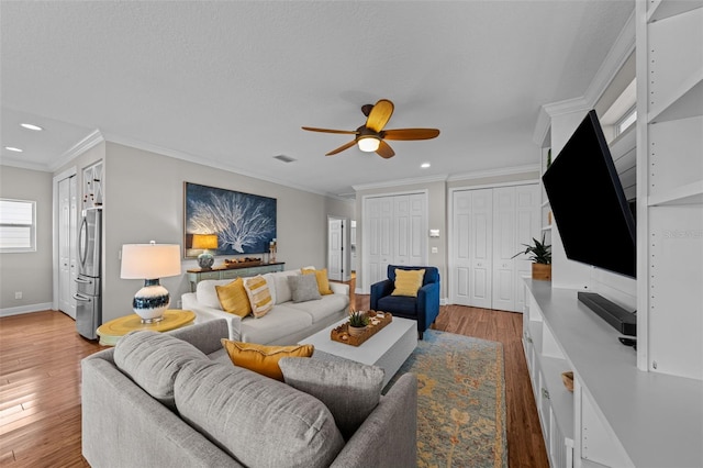 living room with crown molding, ceiling fan, light hardwood / wood-style floors, and a textured ceiling