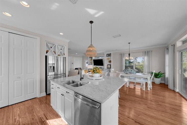 kitchen with white cabinetry, sink, stainless steel appliances, an inviting chandelier, and a kitchen island with sink