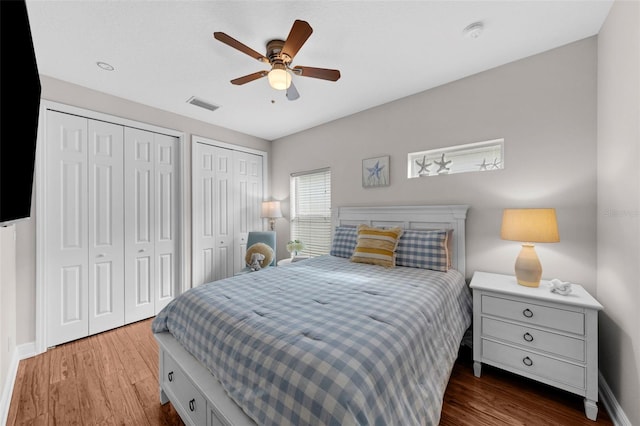 bedroom featuring ceiling fan, dark wood-type flooring, and two closets