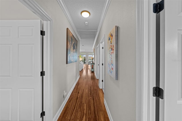 corridor with wood-type flooring, ornamental molding, and a textured ceiling