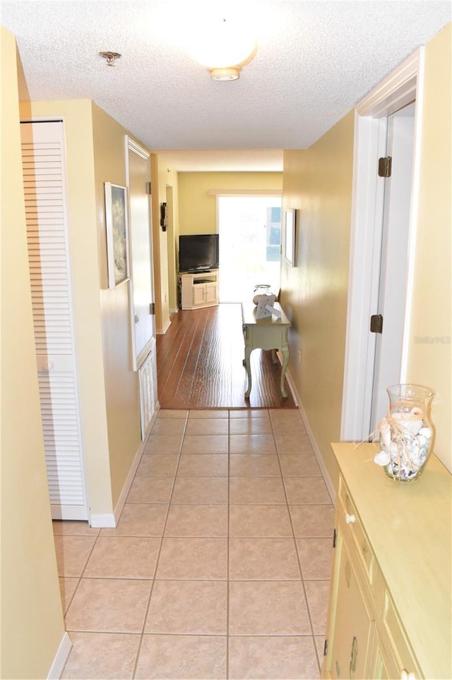 corridor featuring light tile patterned floors and a textured ceiling