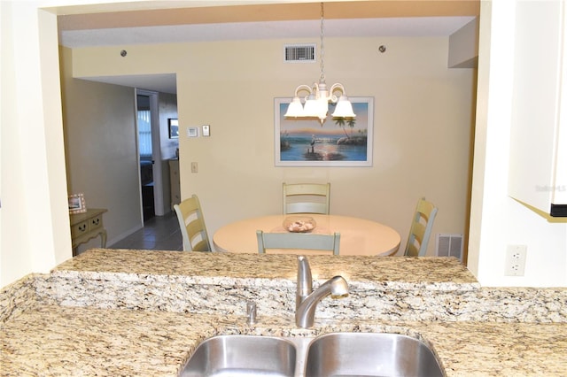 kitchen with light stone countertops, an inviting chandelier, decorative light fixtures, and sink