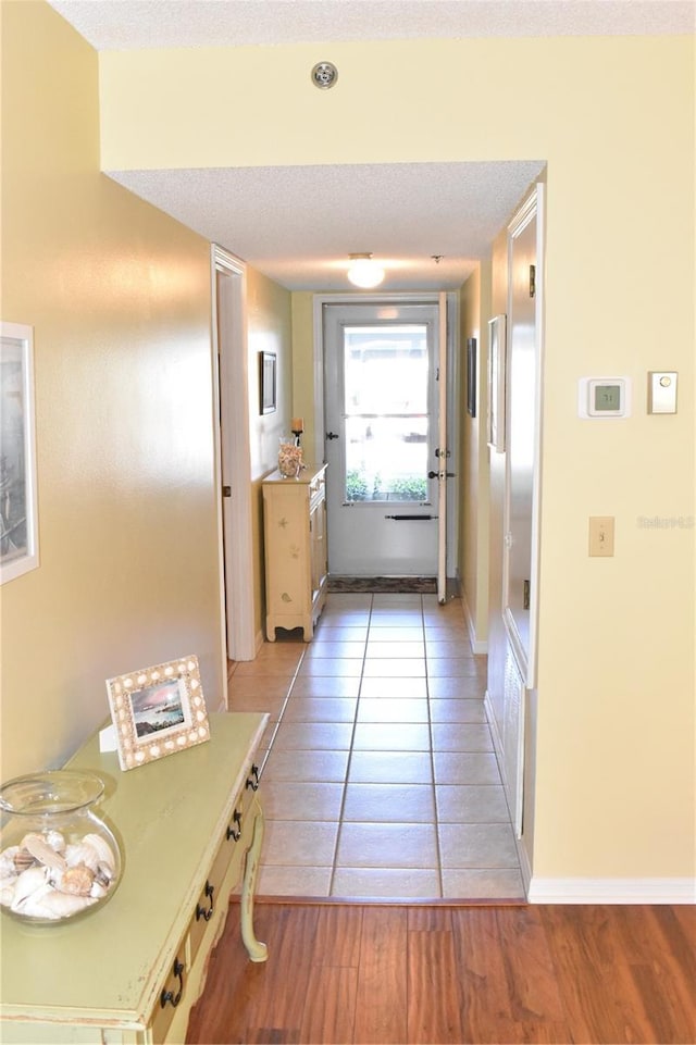 hall with light tile patterned floors and a textured ceiling