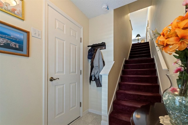 stairs with tile patterned floors and a textured ceiling