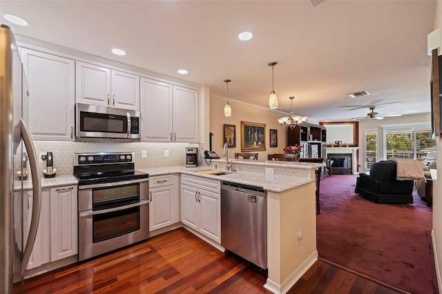 kitchen featuring kitchen peninsula, stainless steel appliances, white cabinetry, and sink