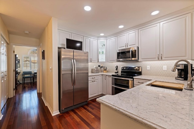 kitchen featuring sink, dark wood-type flooring, stainless steel appliances, light stone counters, and white cabinets